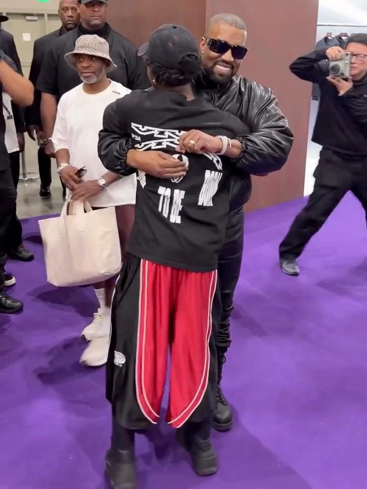 Kai Cenat hugging Ye while wearing the Black Red Worldwide Polyester Jorts